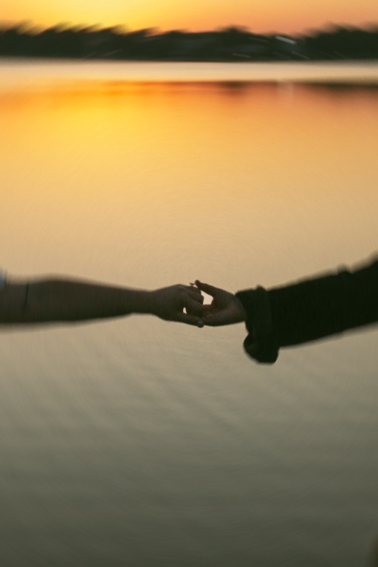 A couple hold hands during their Castle Island Engagement photos with the sea in the backdrop