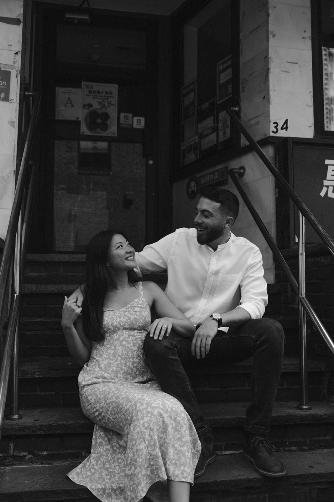 Beautiful couple sit on the steps of a historic chinatown building during their Boston engagement photos!