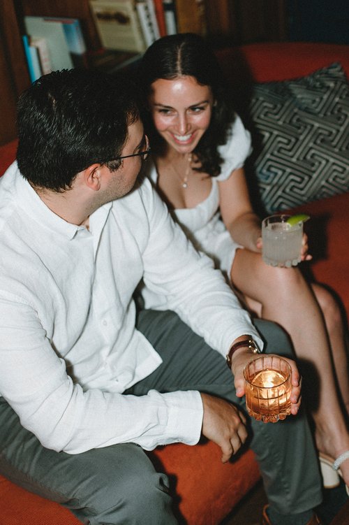 Beautiful couple sit on a couch together sipping cocktails