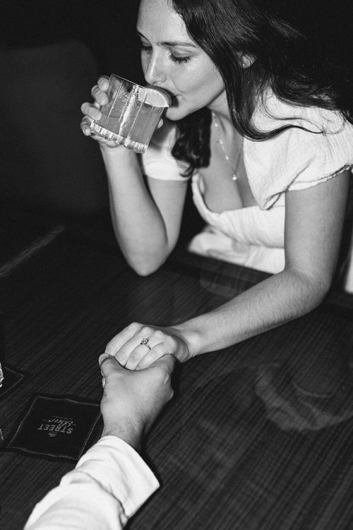 A couple sip cocktails together during their Boston engagement shoot 