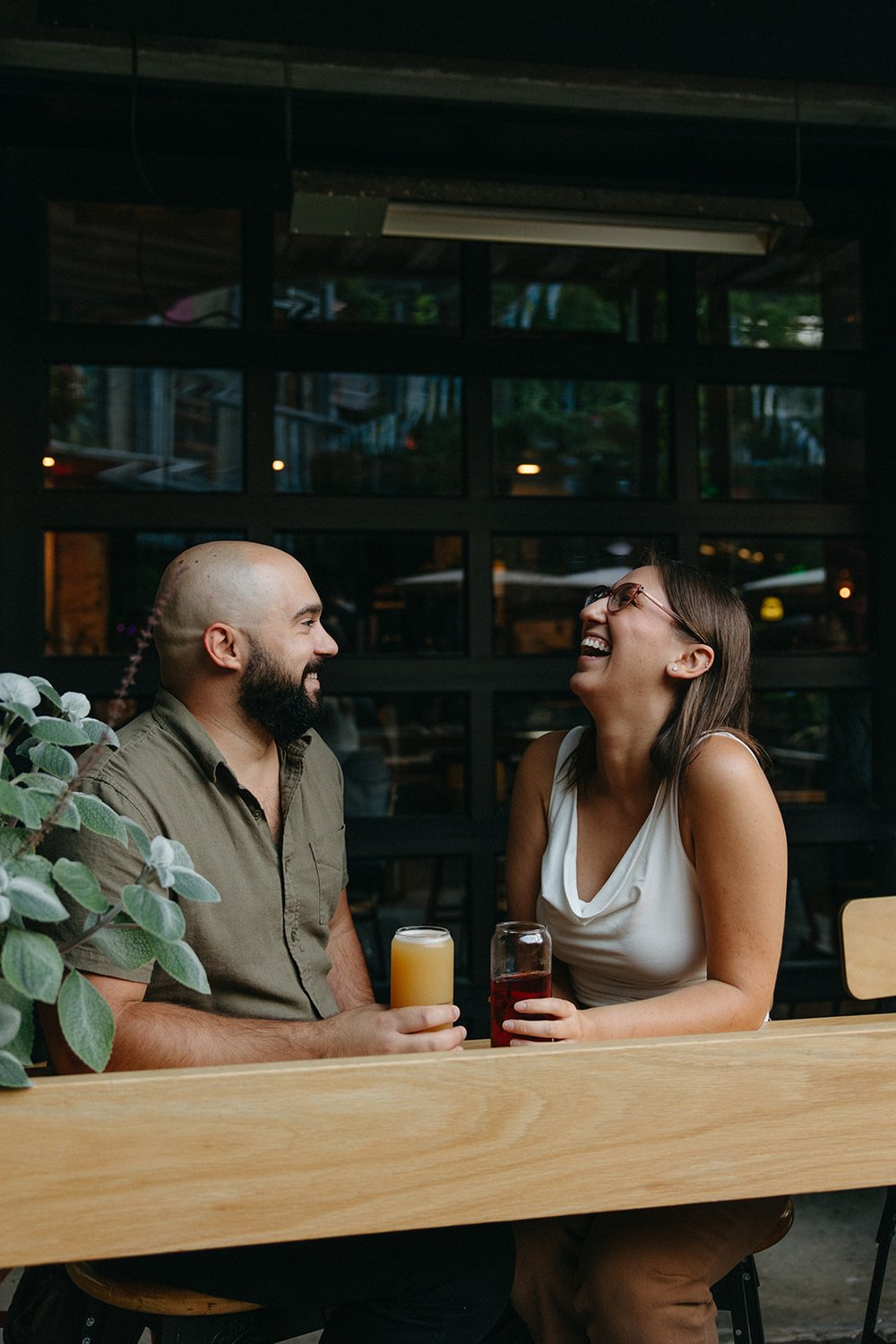 Beautiful couple sit at the bar sharing beers during their Boston engagement photoshoot