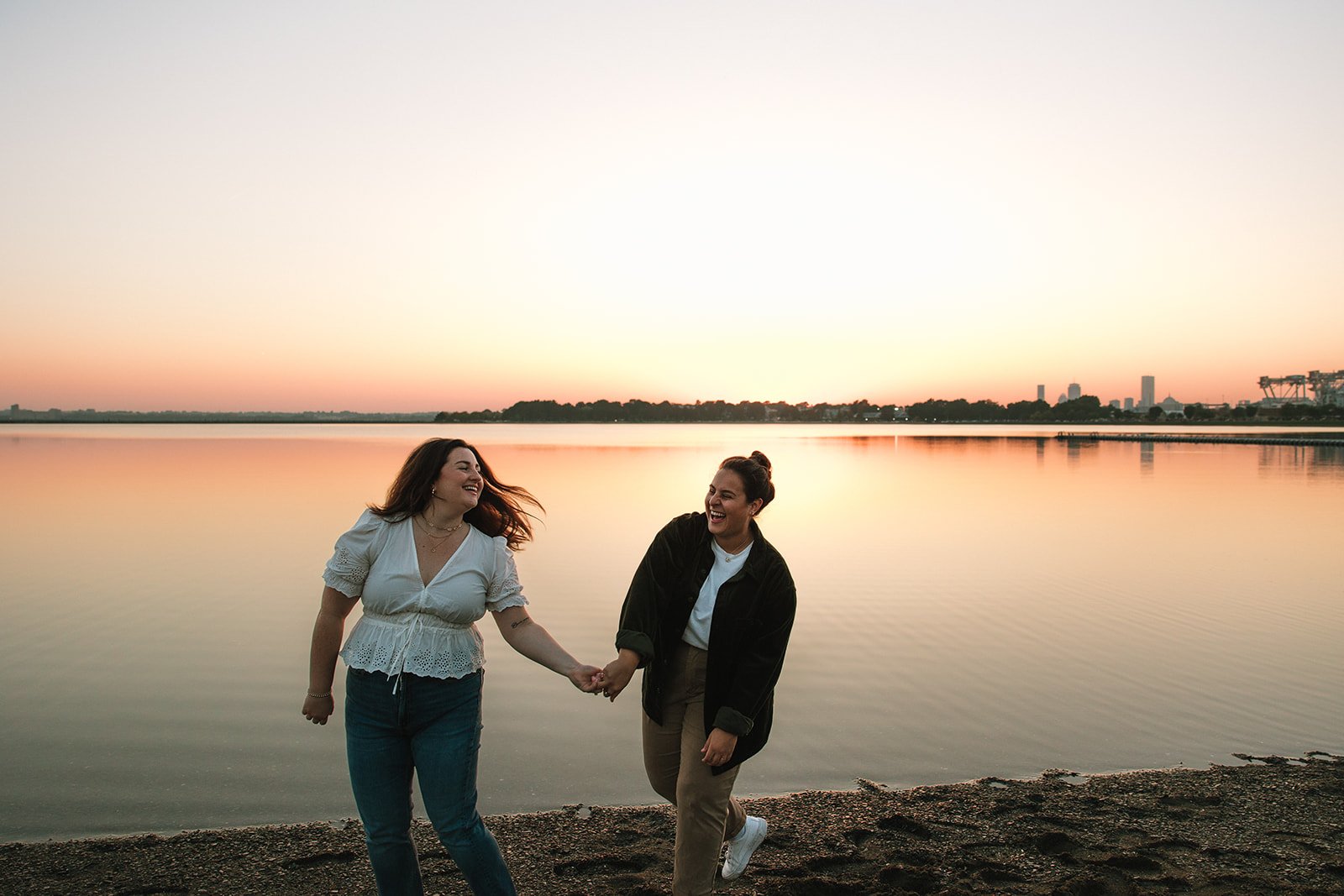 A beautiful couple hold hands by the sea during their Castle island engagement photos 