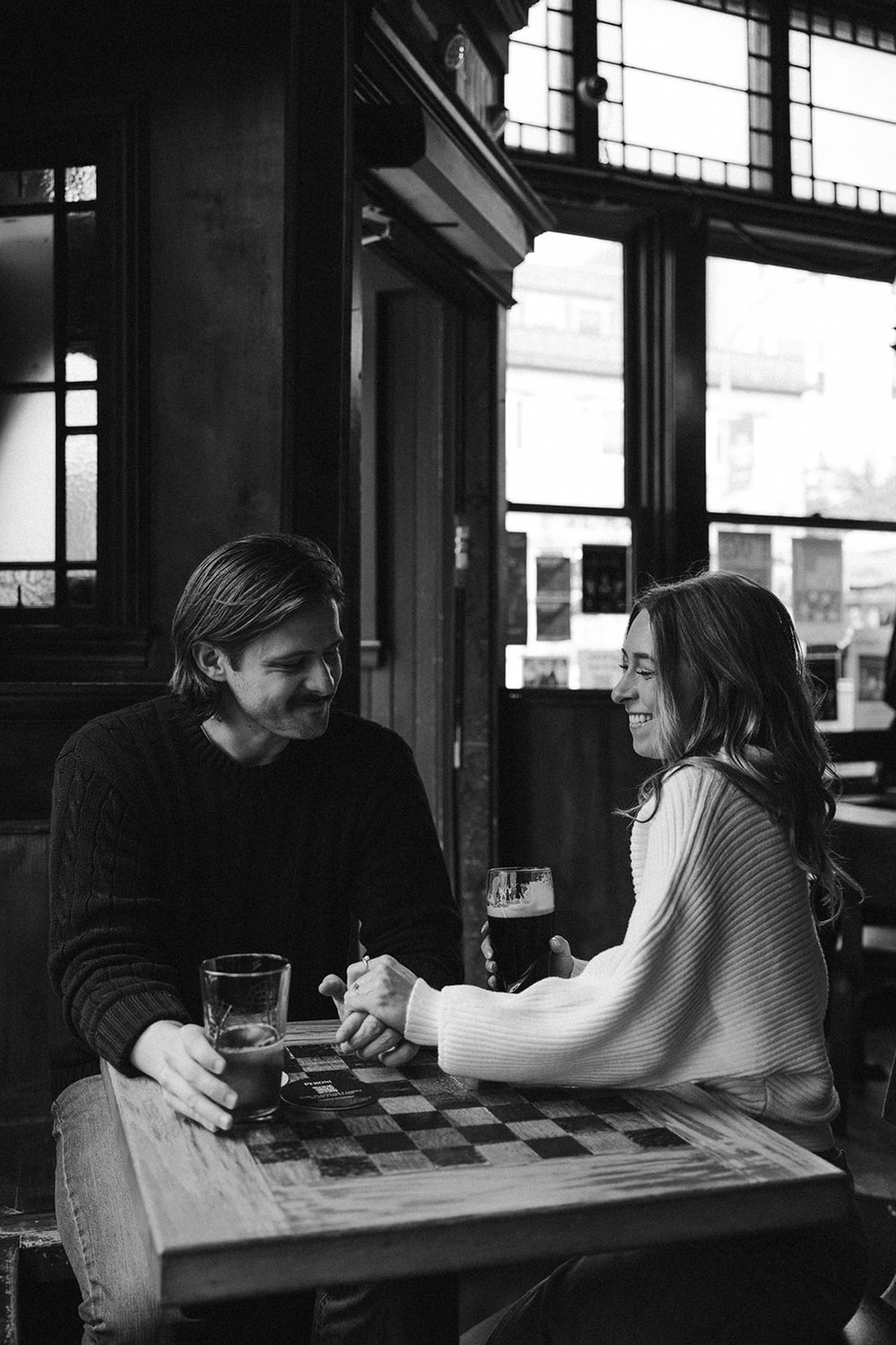 Beautiful couple share a beer together during their Boston engagement photoshoot