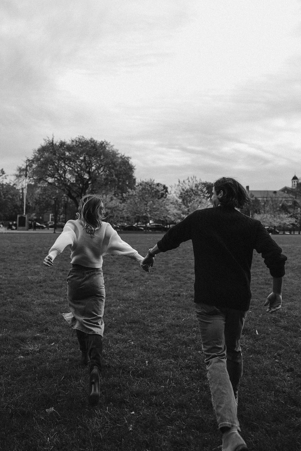 documentary style engagement photo of couple running in open field