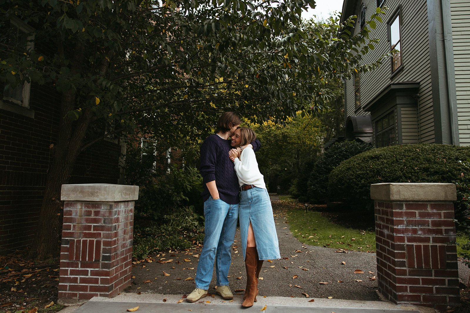 Stunning couple pose together In front of a beautiful New England home during their Boston engagement photos