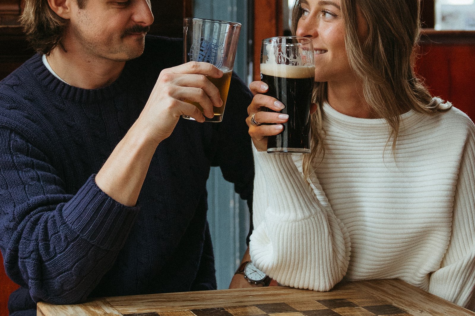 Beautiful couple share a beer together during their Boston engagement photoshoot