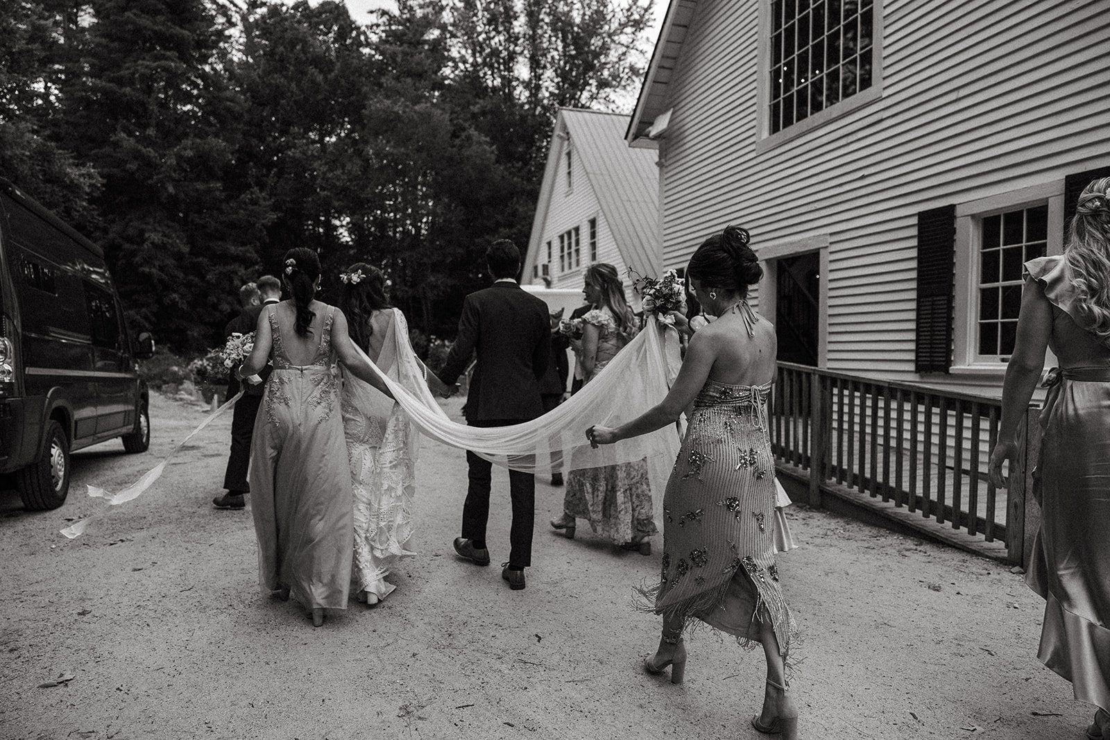 Bridesmaids carry the brides veil as the wedding party moves