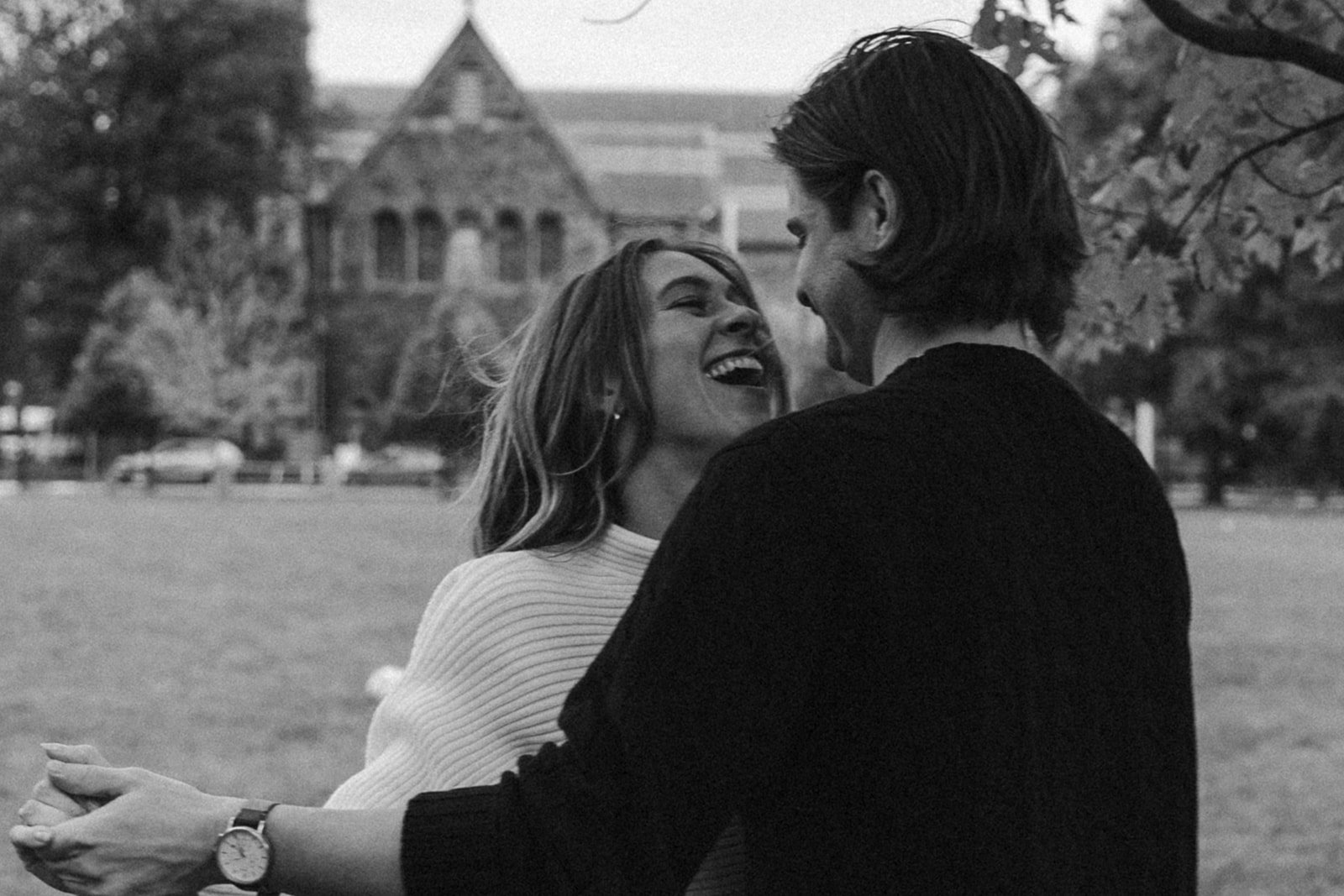 couple laughing with each other in a field during their engagement photoshoot