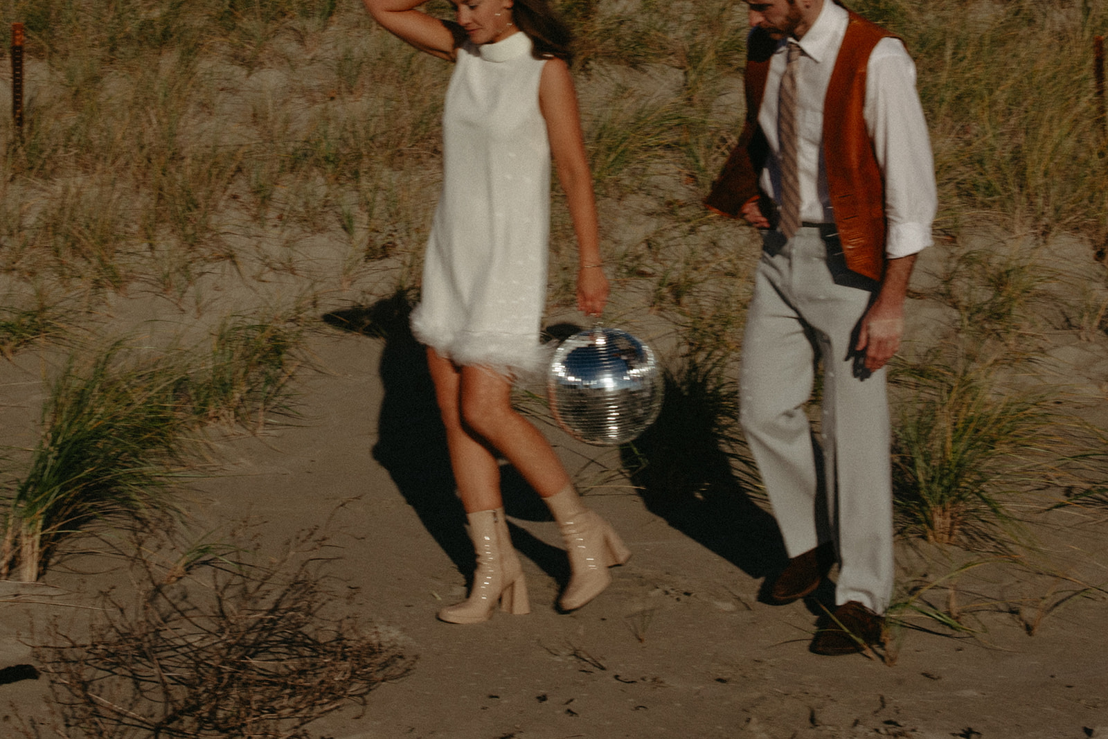 Newlyweds walk on the beach with their disco ball captured by their boston wedding photographer