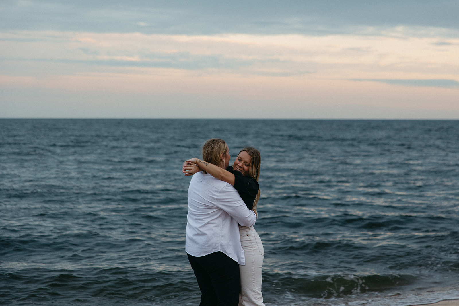 couple hug each other on the shore of plum beach in Massachusetts.