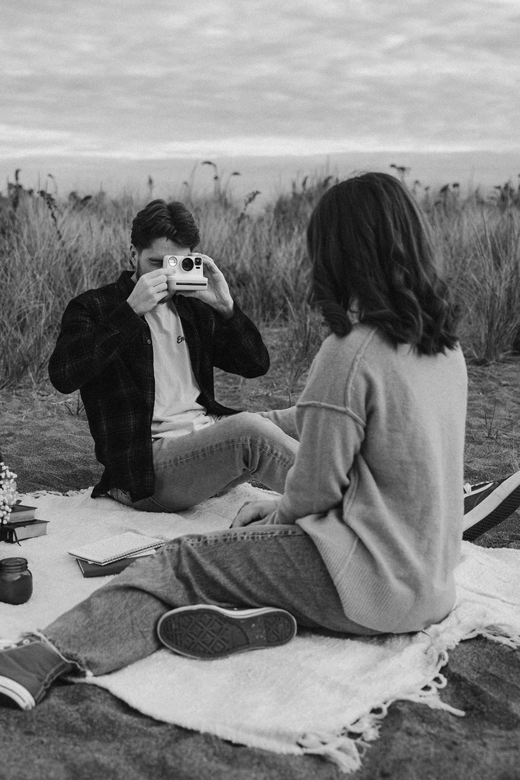 couple taking photos of each other with a disposable camera while on the beach