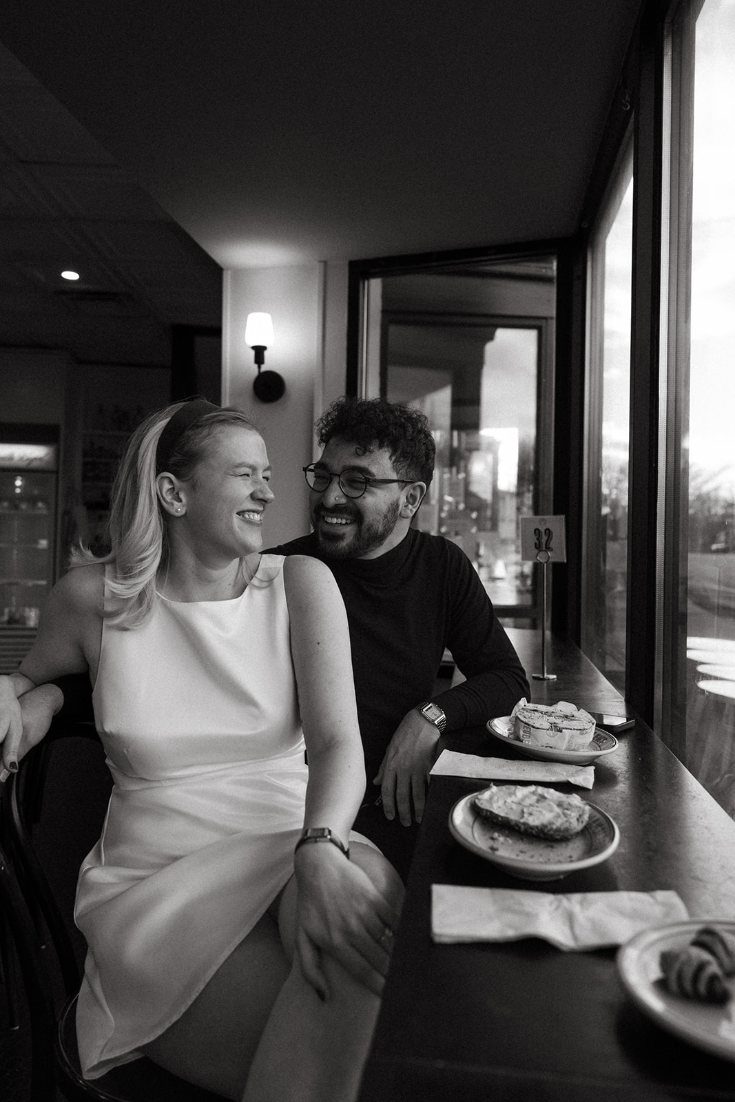 Beautiful couple pose in the cafe eating bagels together