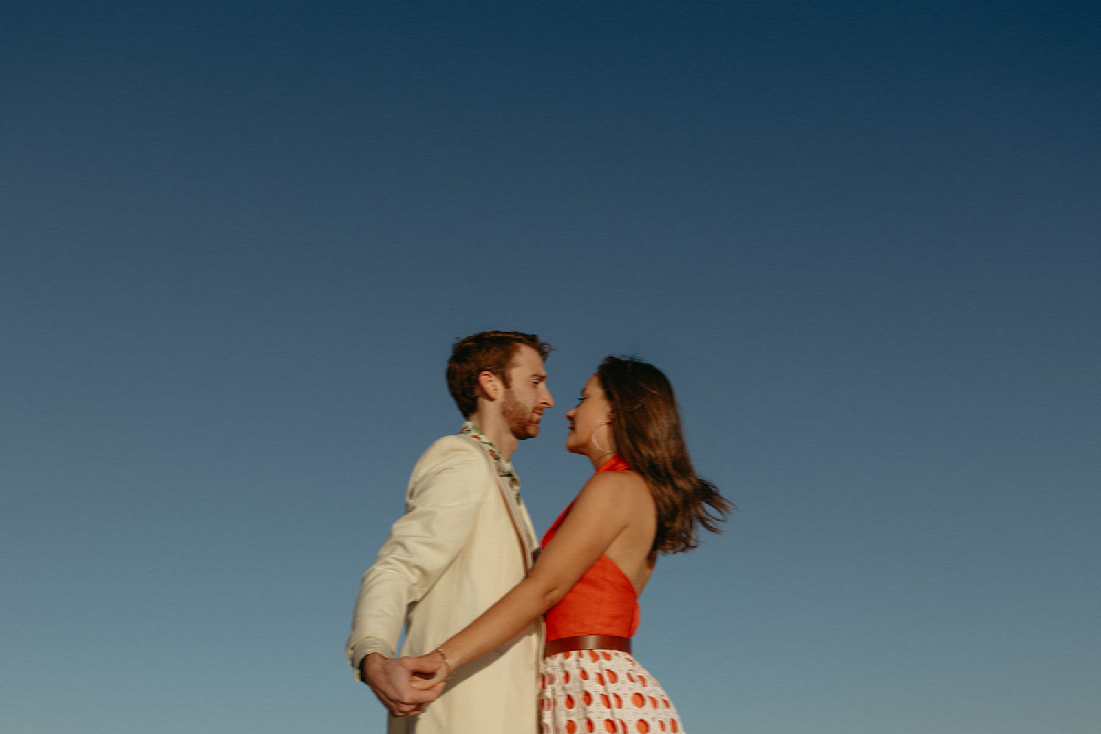 beautiful couple pose together against the  blue sky