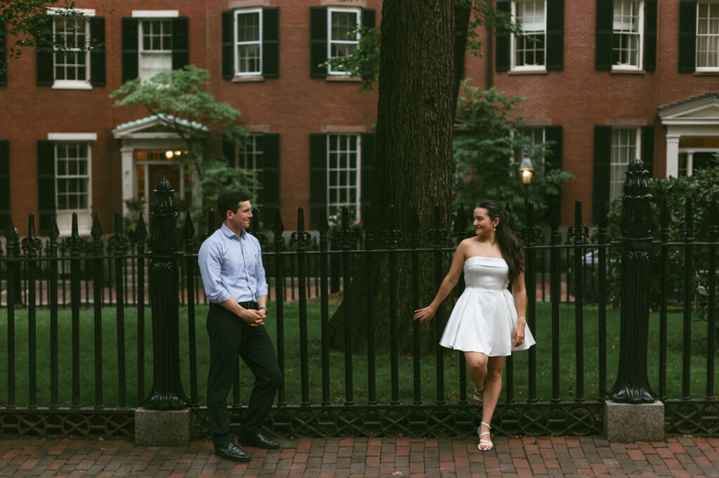 couple poses for engagement photos in front of brown stones in beacon hill boston