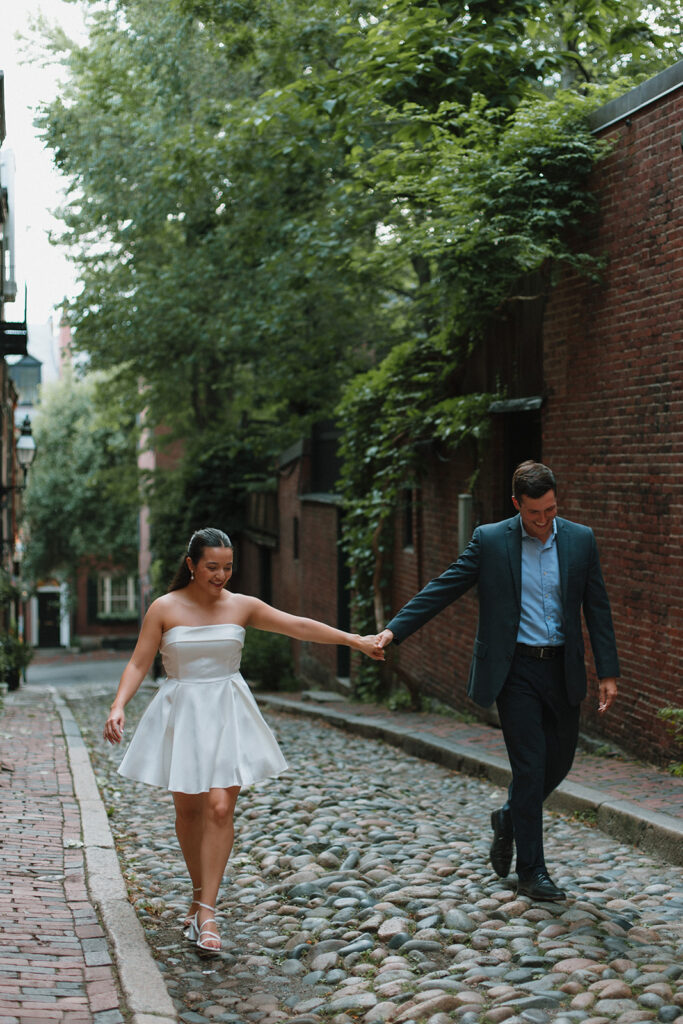 couple walks down acorn street holding hands in beacon hill for engagement photos