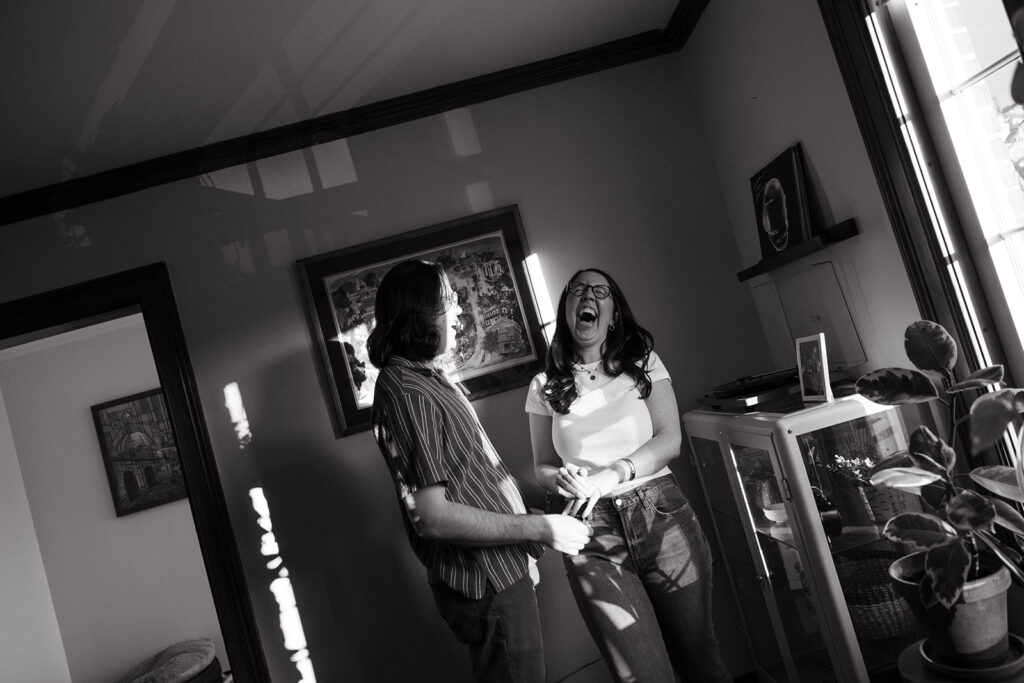 Couple laughs together in their apartment during engagement session