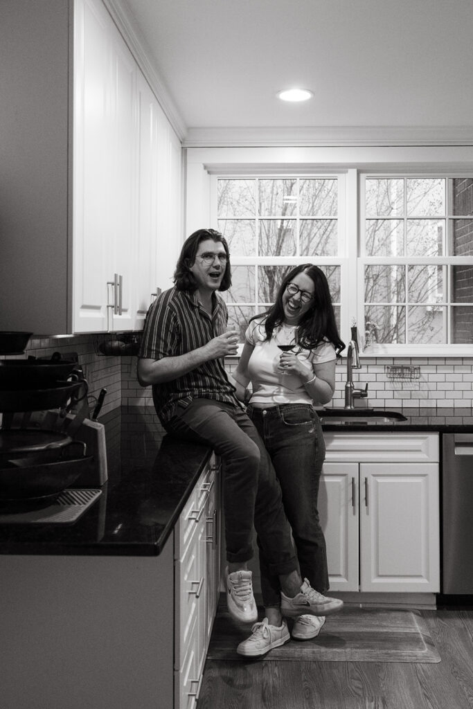 couple drinks wine in kitchen during romantic engagement session at home