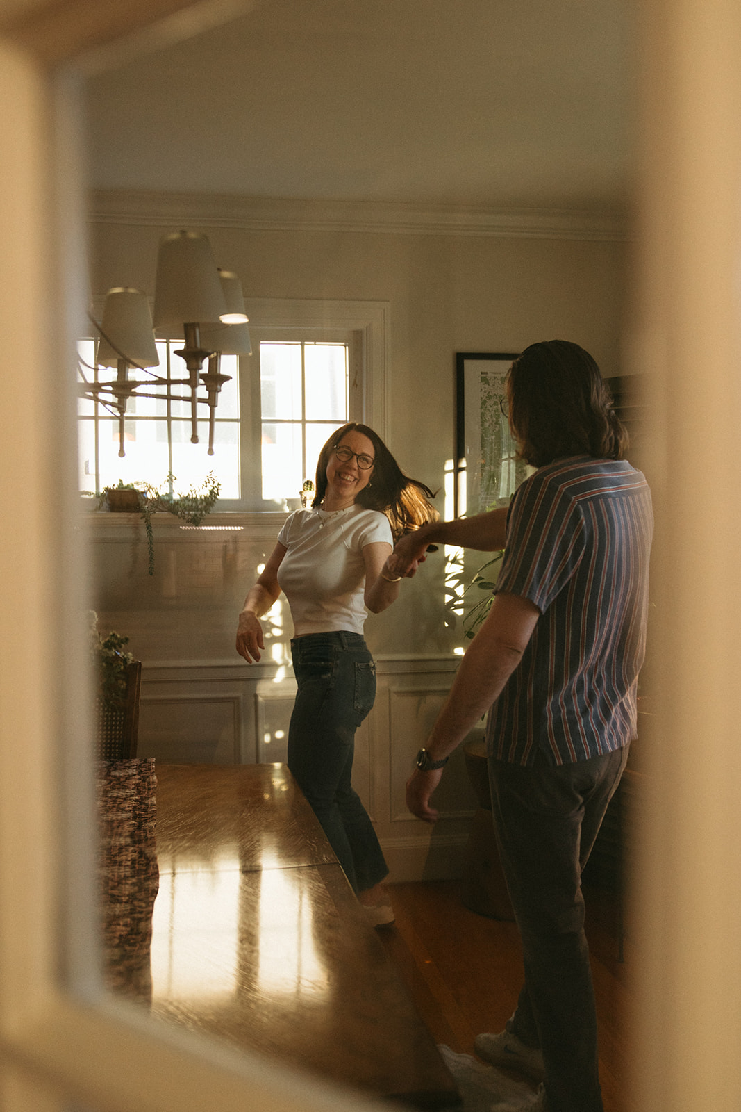 Couple dances around kitchen during cinematic engagement session in their boston apartment