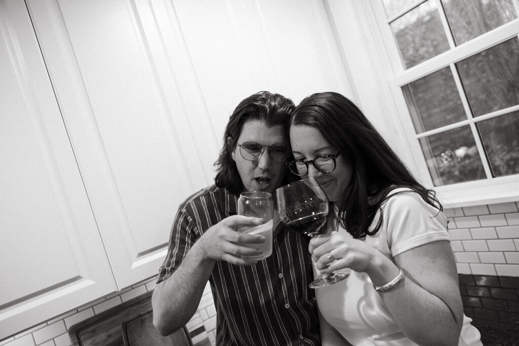 couple toasts during documentary style engagement session at their boston apartment