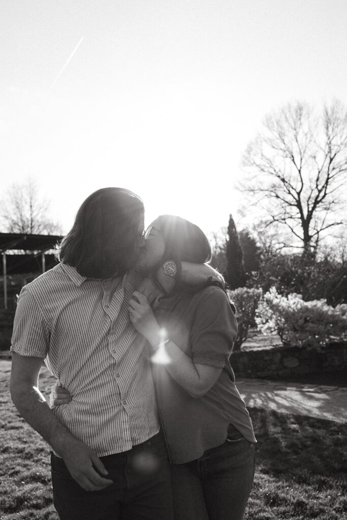 couple runs and kisses during engagement photos at harvard university's arnold arboretum