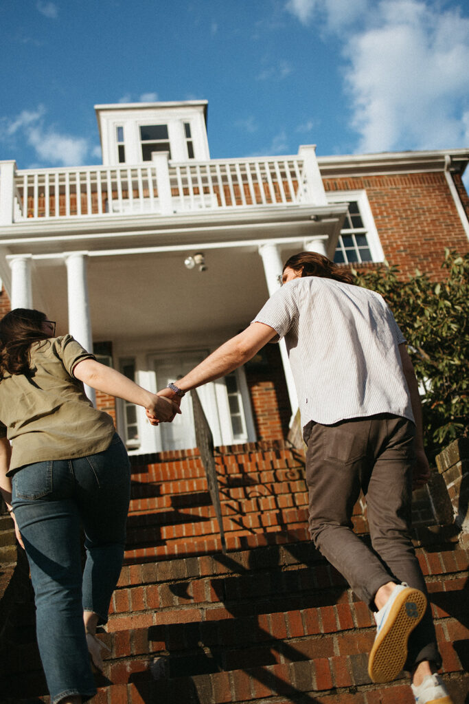 Couple walking up the steps of their apartment during candid engagement photos in Boston