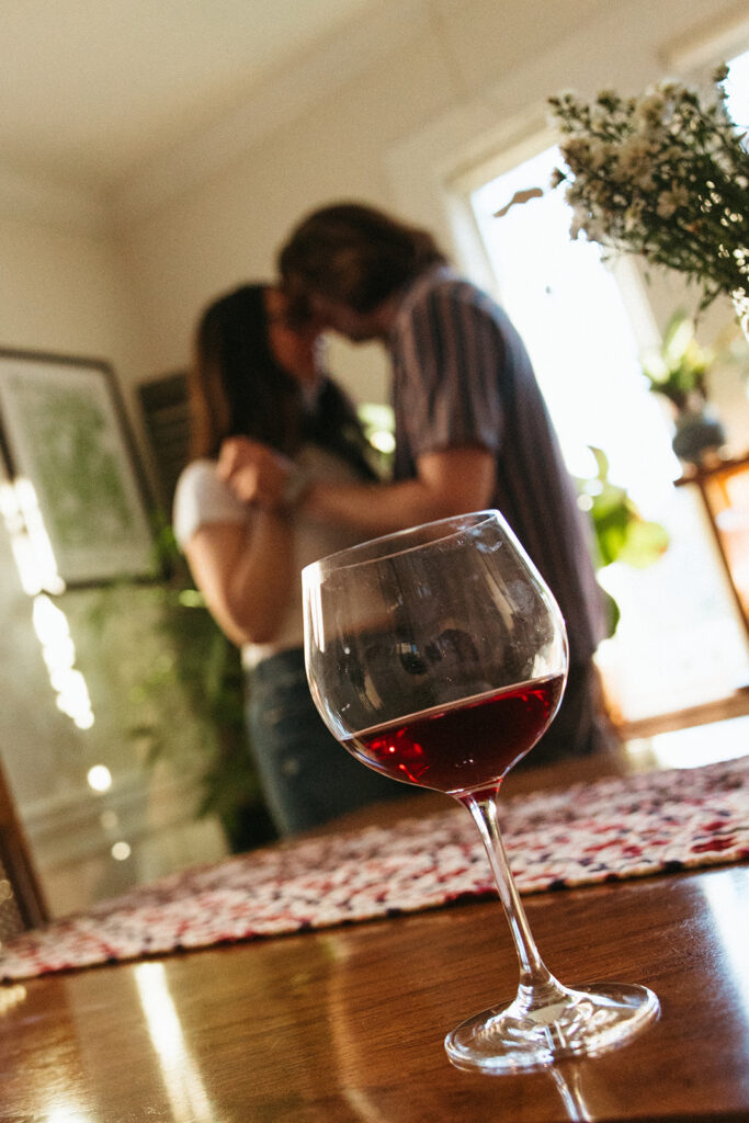 couple dances in kitchen with wine during cinematic engagement session