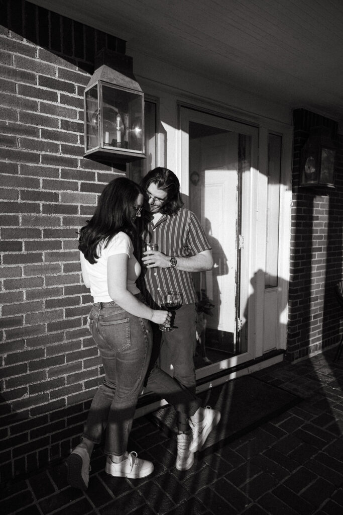 Couple drinking wine on their front steps during film engagement session in Massachusetts