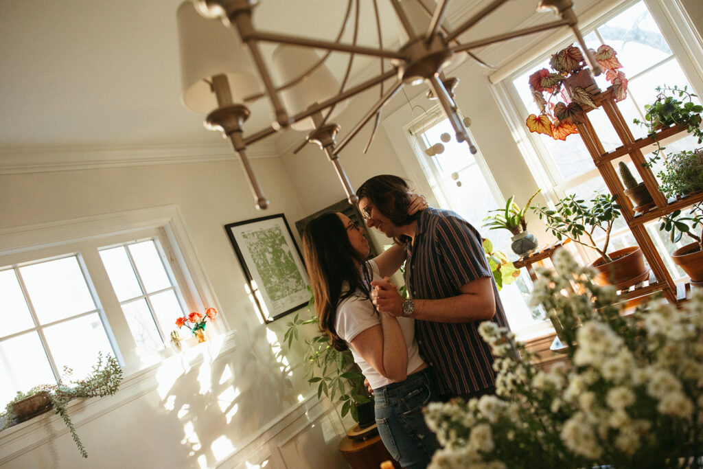 Couple dances around kitchen during romantic golden hour engagement session