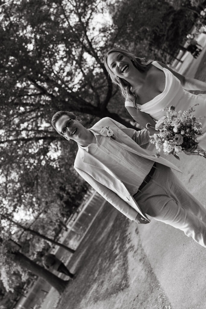 Bride and groom black and white photo laughing walking through Boston Common