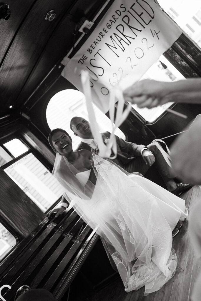 bride and groom ride in trolley with just married sign after wedding ceremony in salem massachusetts