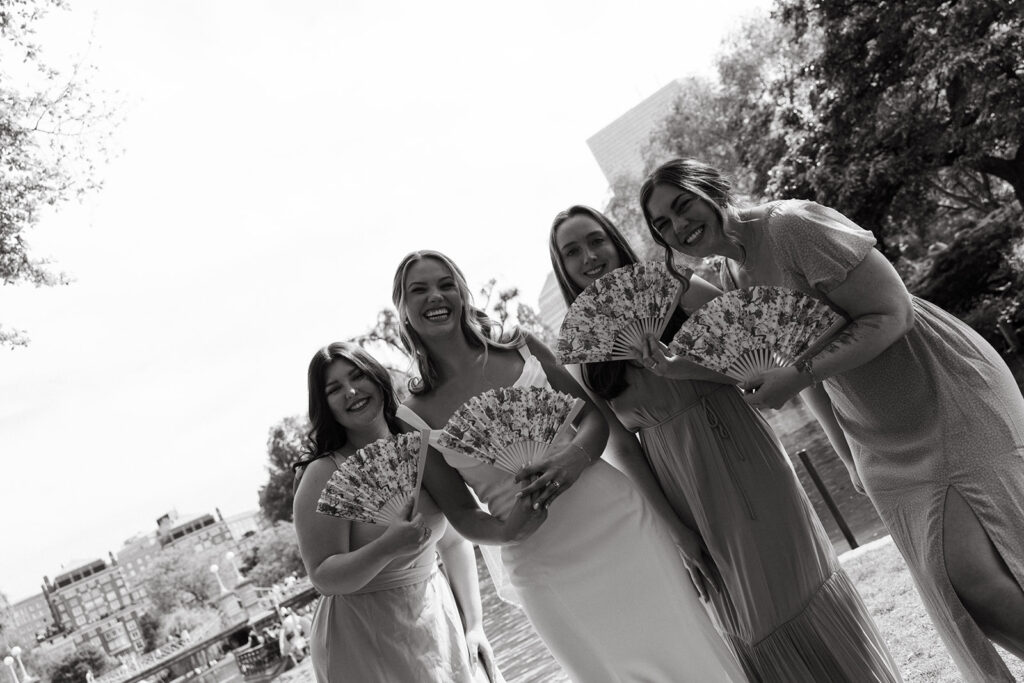 candid black and white photo of bridesmaids with fans at summer boston wedding