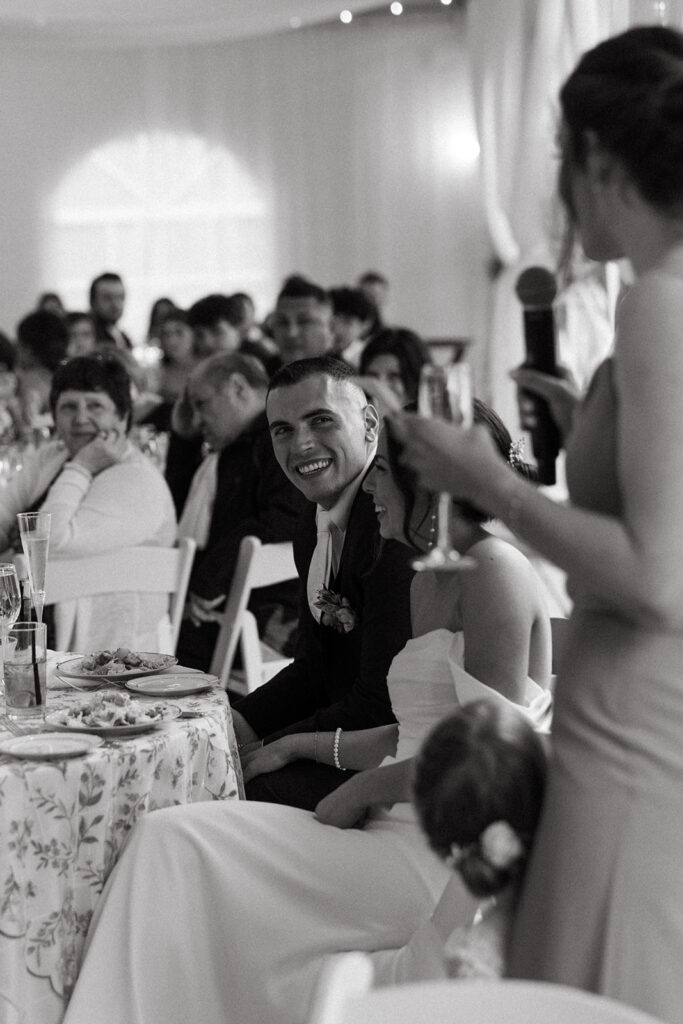 groom laughs and listens to toasts during wedding reception in beverly massachusetts