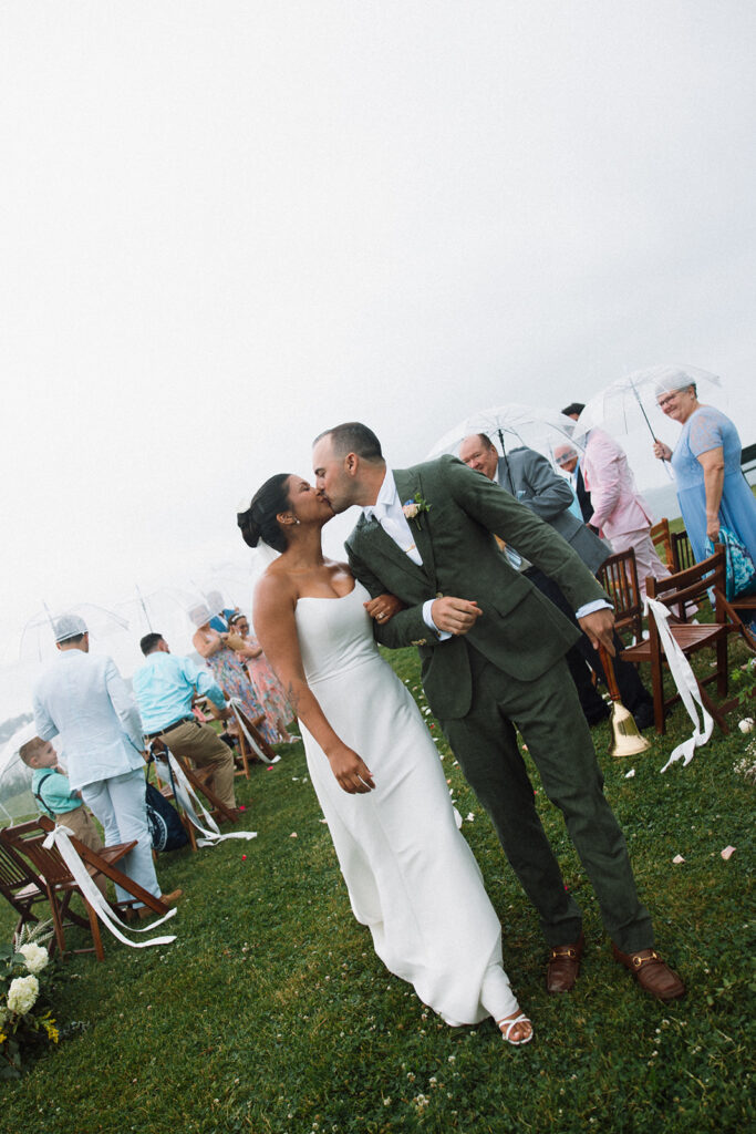 couple kisses down aisle during rainy outdoor wedding in salem mass