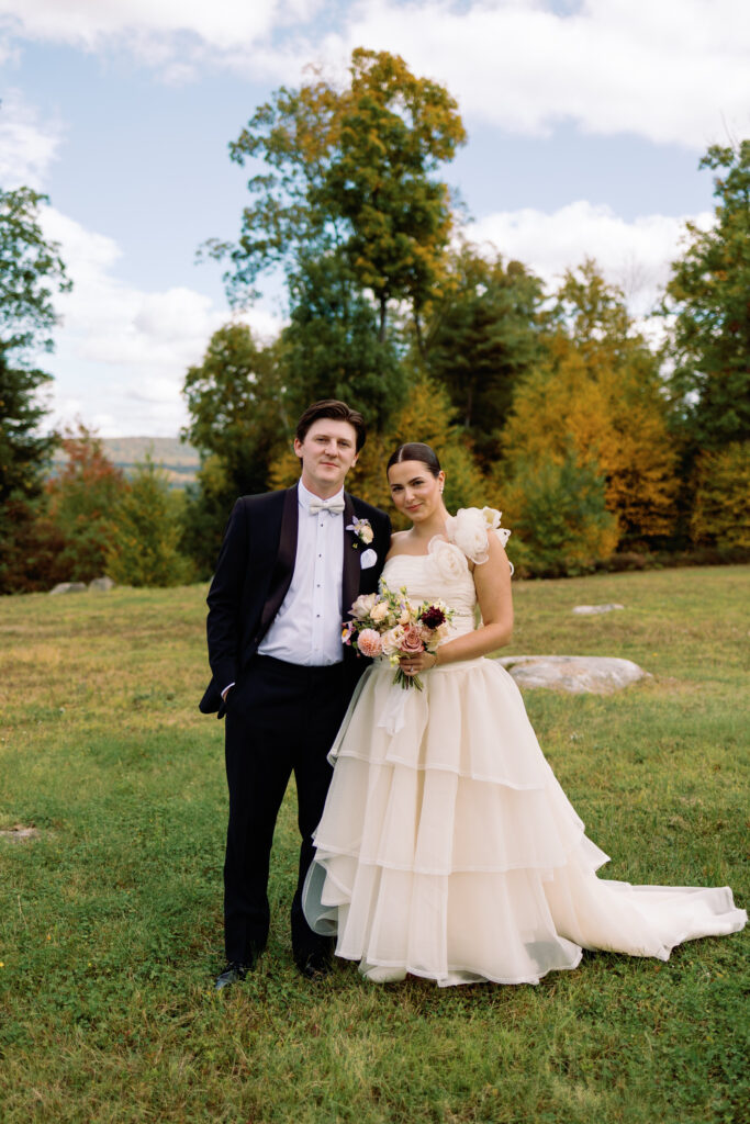 vibrant and filmy wedding portraits of bride and groom in field with fall foliage in new hampshire