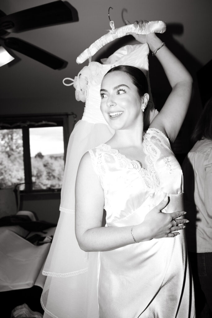 black and white editorial photo of bride carrying her vintage wedding dress