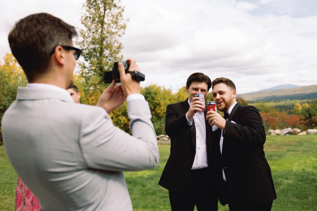 groom and groomsman toast while friend records video on camcorder