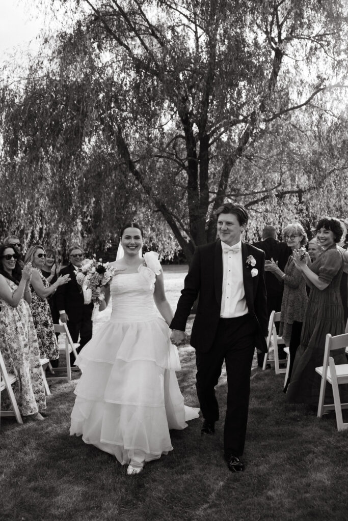 bride and groom walk down wedding ceremony aisle at their vintage backyard wedding