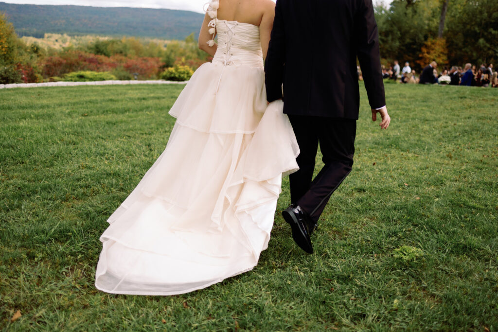 groom carries brides dress while they enter cocktail hour