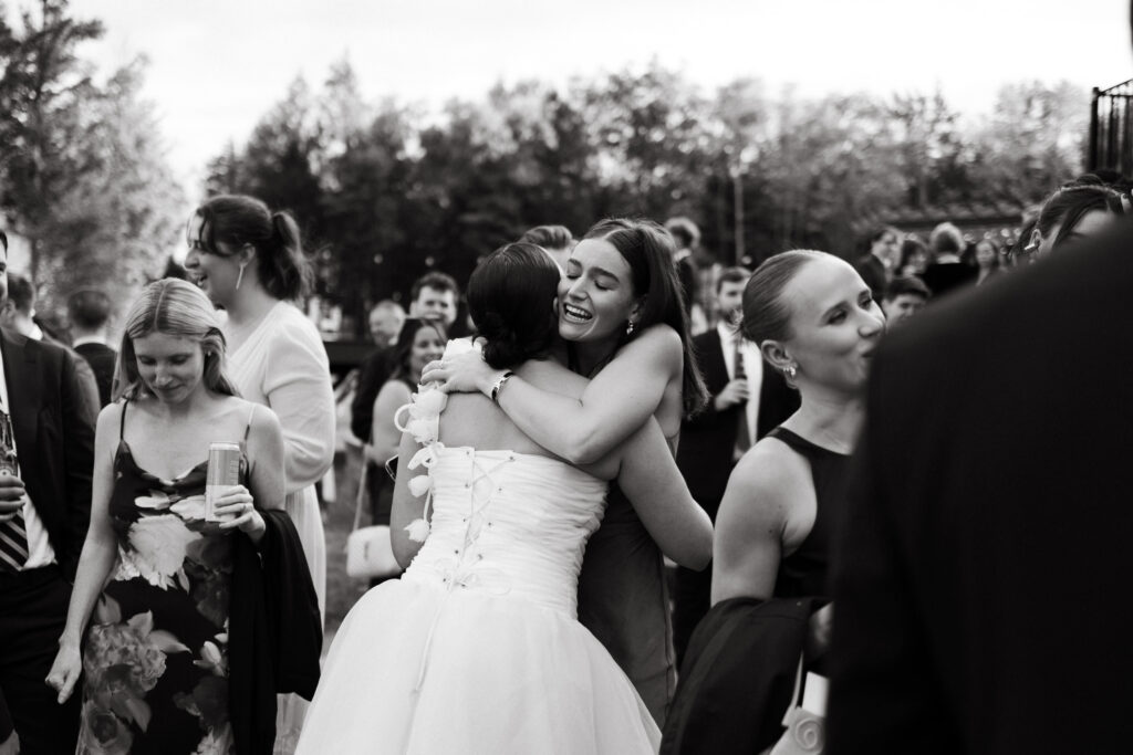 bride hugs friend during cocktail hour