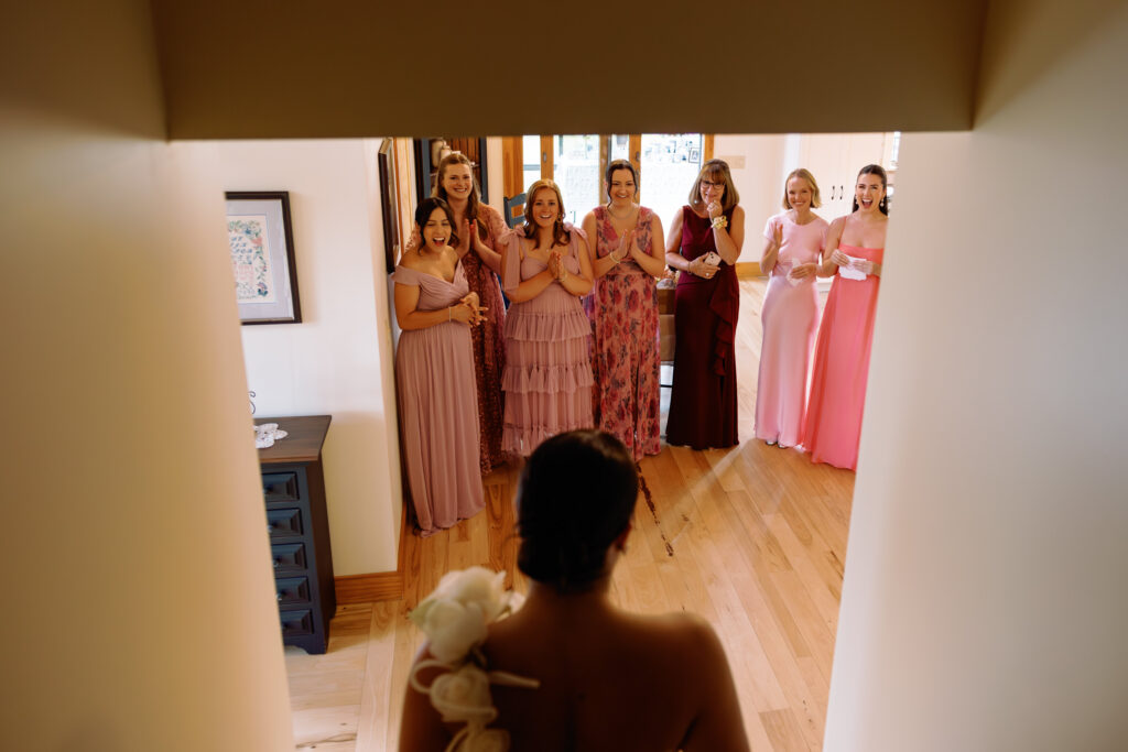 bridesmaids smile and cry while seeing the bride for the first time during their first look