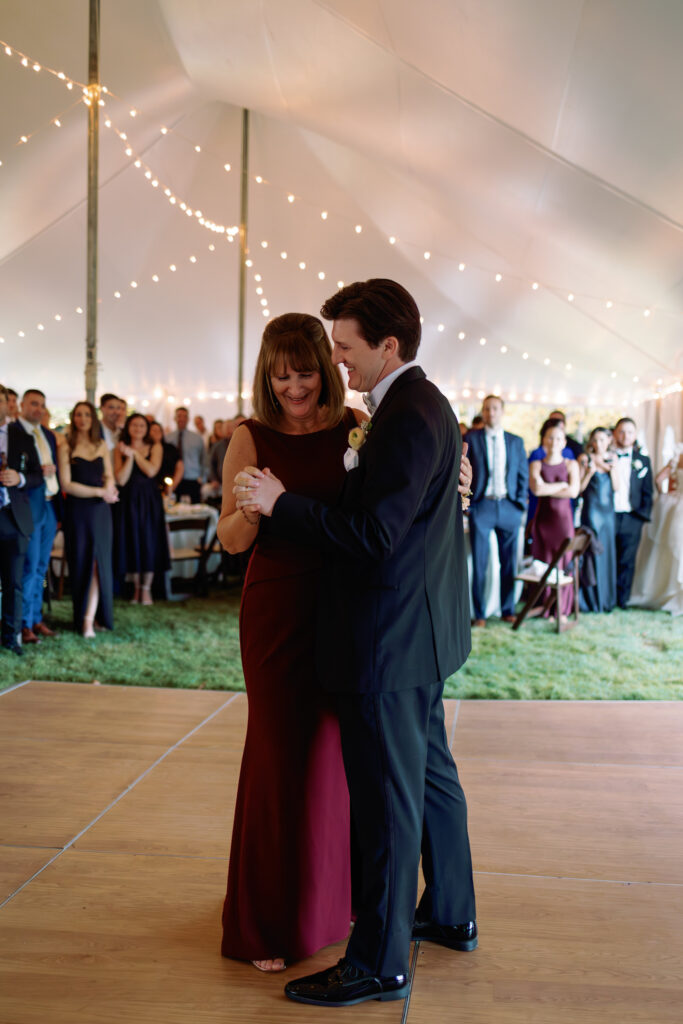 groom dances with mom in tented backyard wedding