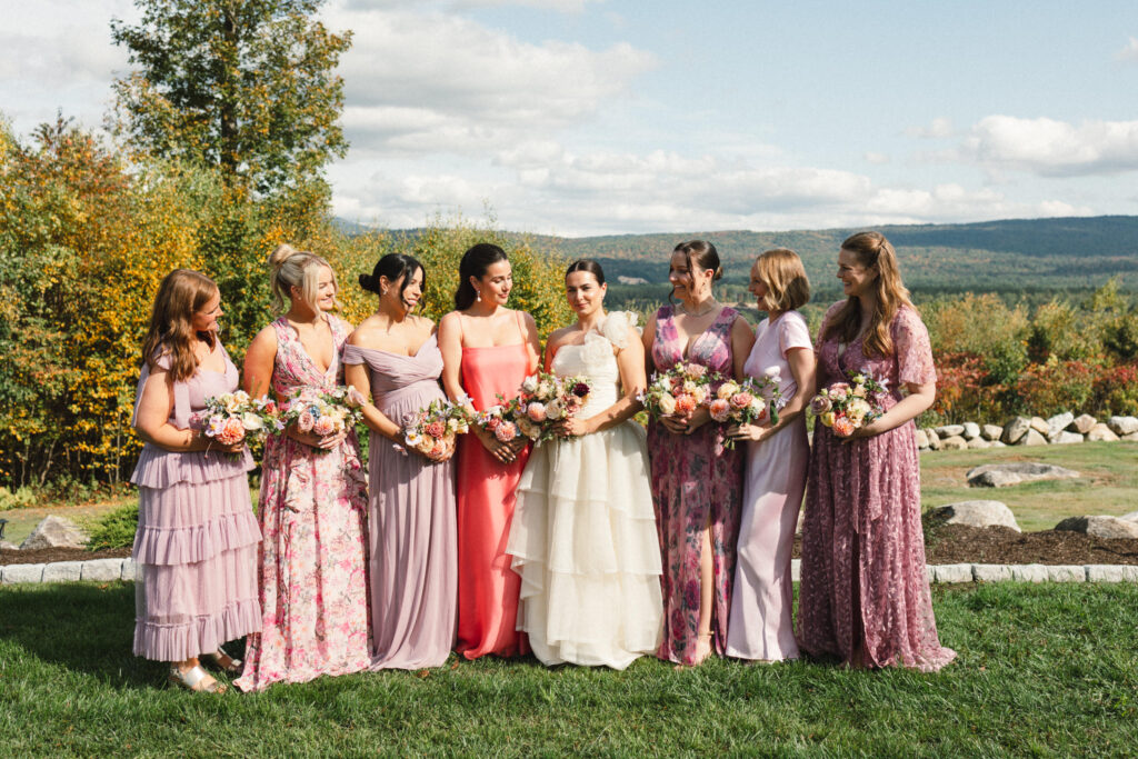 bridesmaids wearing mismatched shades of pink pose with bride wearing vintage wedding gown