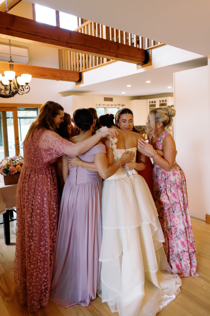 candid wedding photo of bride hugging her bridesmaids