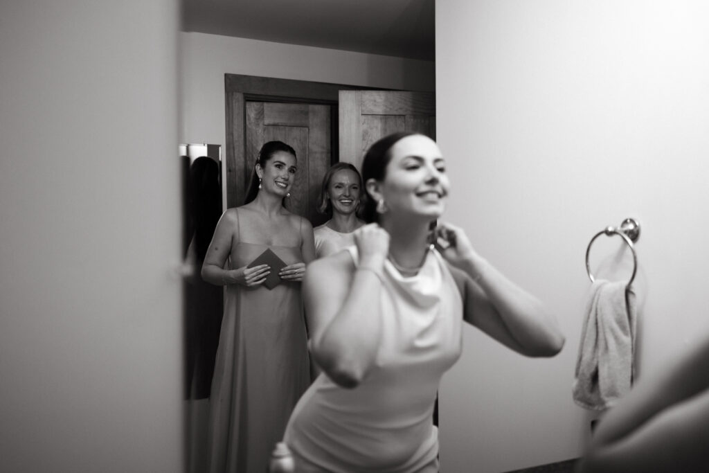bride changes into second wedding outfit while her friends help