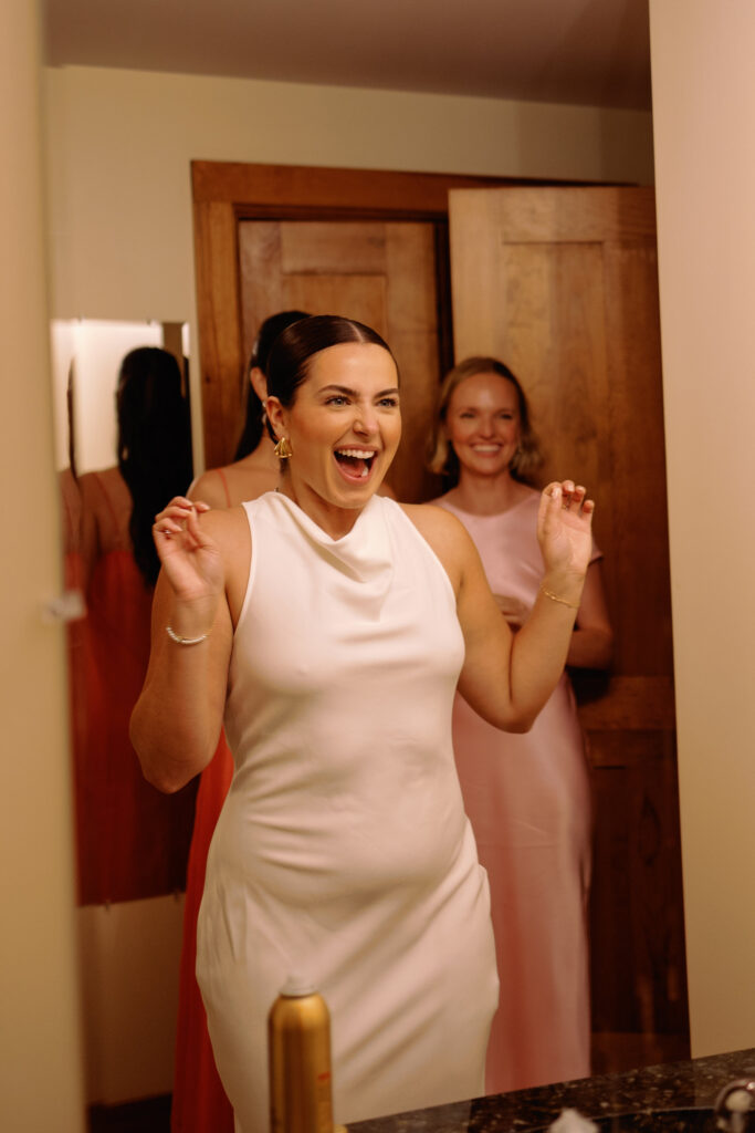 bride changes into second wedding outfit while her friends help