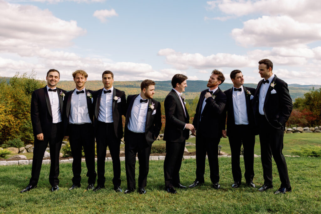 candid photo of groomsmen fixing each other's ties during portraits