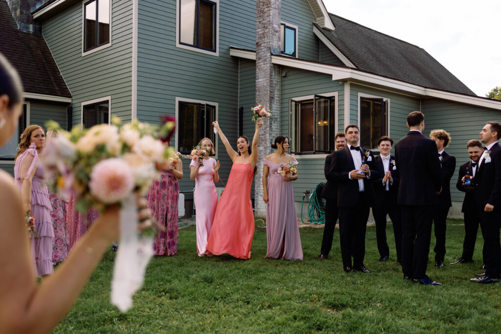 bridesmaids cheer for bride and groom during portraits at new hampshire backyard wedding