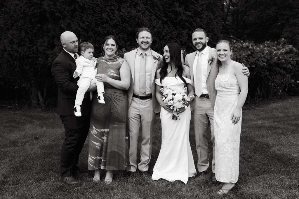A groom, bride, and their family stand together for a photo. 