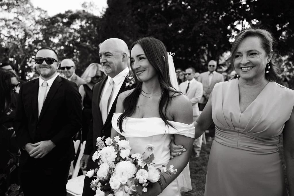 A bride walking down the aisle with her parents. 