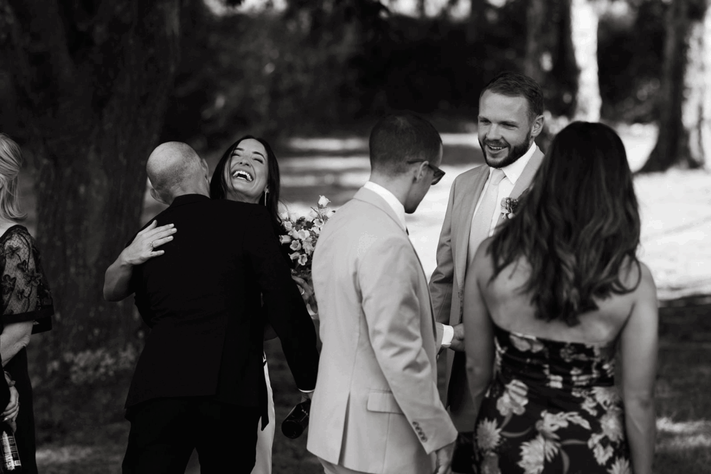 A groom and bride hug wedding guests in a receiving line.